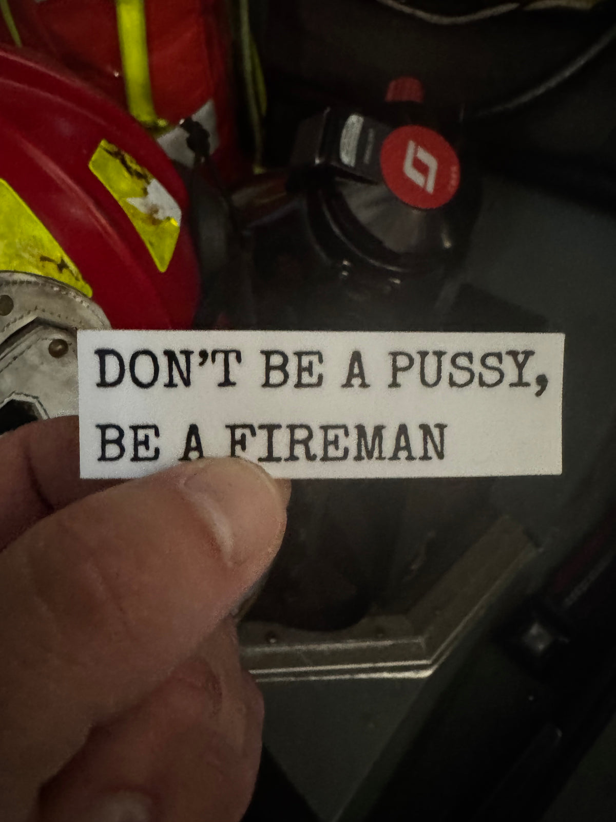 White rectangular firefighter sticker reading “DON’T BE A PUSSY, BE A FIREMAN” in black typewriter-style lettering.